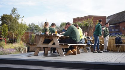 People sat on picnic benches on a raised platform