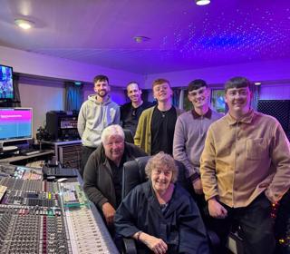 People in front of a sound studio mixing desk