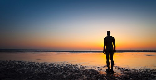The sunset at Crosby beach with an Anthony Gormley Iron Man statue at the front of the image