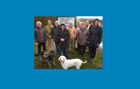 Cllr Liz Dowd and members of Rimrose Valley Friends group and their dogs stood in front of a park notice board