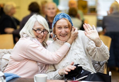 Two older people smiling and waving
