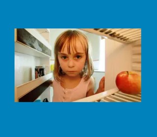 Sad looking child peering into empty fridge