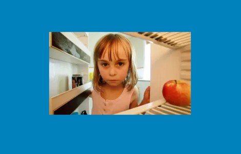 Sad looking child peering into empty fridge