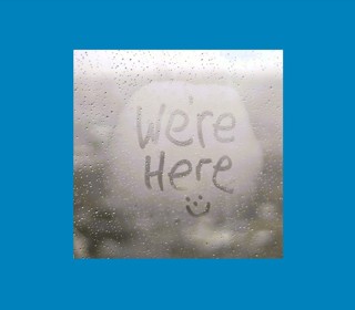 Steamed up window with We're Here and a smiley face drawn in the steam