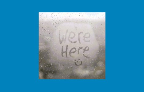 Steamed up window with We're Here and a smiley face drawn in the steam