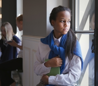 A student looking out the window holding a book