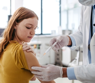 Doctor injecting vaccine into a teenage girl's arm.