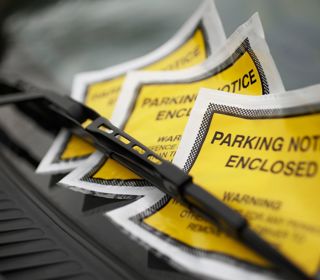 A photo of a parking fines underneath a windshield wiper