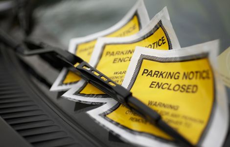 A photo of a parking fines underneath a windshield wiper